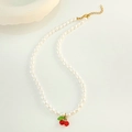 Close-up of white pearl necklace with red cherry pendant and adjustable gold chain - Pearl Cherry Necklace (12028) / Gold
