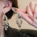 Macro shot of gold tassel earrings featuring grey teardrop crystals worn by a model - 925 Sterling Silver Earring Post Grey Crystal Tassel