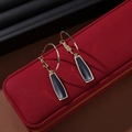 Golden hoop earrings with black geometric pendant on red textured jewelry box display - Vintage Ear Drop S3362