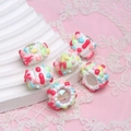 Macro shot of colorful hand-painted DIY resin beads on a pink lace decorative surface - Seven-color Flower