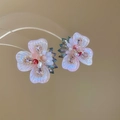 Vista macro di orecchini a fiore con ago in argento, cristalli lucidi e perle finte - Rosa