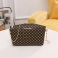 Vintage crossbody bag with brown clover pattern and gold chain strap on table - Khaki