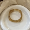 Detailed top view of amber resin bangle with marbled texture on a white ceramic plate - Geometric Rhombus / Inner Diameter 65mm / Transparent Yellow