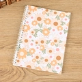 Spiral notebook with fresh orange daisy floral cover on a light wood background - A5