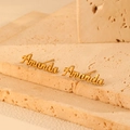 Detailed view of custom 18k gold plated Amanda name earrings on textured travertine stone - Gold Earrings