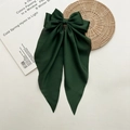 Dunkelgrüne Satin-Haarschleife mit langen Bändern auf minimalistischem beigem Hintergrund - Dunkelgrün