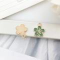 Detailed close-up of cherry blossom enamel pendant with green oil and golden finish - Sakura