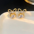 Elegant gold bow earrings with sparkling cubic zirconia crystals on white ceramic plate - A Pair Of Gold Leds-163