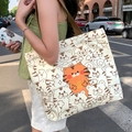 Off-white canvas tote bag with cartoon tiger print and brown shoulder strap on a street - Lucky Tiger - Beige