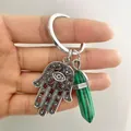 Macro detail of silver Hamsa Hand keychain with green malachite hexagonal crystal pillar - Malachite green
