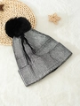 Metallic silver knit beanie with black faux fur pom pom on a white faux fur background - One Size / Silver