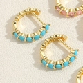 Détail de boucles d'oreilles huggies dorées avec zircons ovales roses et turquoise - Zircone Bleu Turquoise