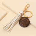 Detalle del colgante MAMA de madera con borla blanca y llavero dorado para bolsos - Blanco