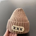 Beige baby knit dinosaur hat with ribbed texture and decorative black cross patch - Children X-Label Hat - Khaki