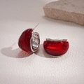 Detailed macro view of red resin C-shape earrings with silver-tone metal edges on stone - Red