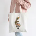Artistic white fox canvas tote bag with floral pattern shown on a shoulder - Style C12-Fox Tangled In Plants