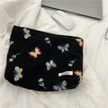 Detailaufnahme der schwarzen Tasche mit Schmetterlingsstickerei auf Bettwäsche - Bestickter schwarzer Schmetterling