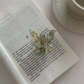 Detail der Schmetterlings-Haarklammer mit blauem Marmormuster auf einem offenen Buch - Grünes Muster