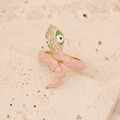 Golden snake ring with pink enamel and green zircon accents on stone surface - Pink