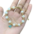 Close-up of pearl and gold bead bracelet featuring a blue gemstone heart pendant - Pearl Metal Bead Blue Eye Pendant