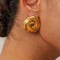Detail of twisted knot gold earring with high-shine metallic texture worn by a model - 18K Gold / Gold