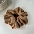 Nahaufnahme von karamellbraunem Satin-Haargummi mit glänzender Textur und Seidenfalten - Hellkaffee