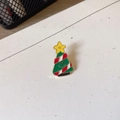 Macro shot of cartoon Christmas tree enamel brooch with golden metal edges and smiley face - Christmas Tree