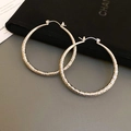 Détail de boucles d'oreilles créoles argentées en C avec texture de métal martelé brillant - Grand / Argent