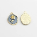 Macro detail of oval alloy pendant with blue enamel rose and textured gold reverse - Blue-Grey