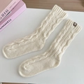 Detail of cream cable knit wool socks featuring a minimalist brown leather logo patch - One Size / Milk White