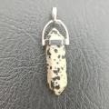 Spotted dalmatian stone hexagonal point pendant with silver metal bail on leather background - Dalmatian Jasper