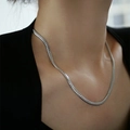 Collana cubana minimalista in acciaio al titanio argento indossata dalla modella in primo piano - Catena a serpente piatta / Argento