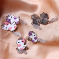 Detailed close-up of cartoon cat magnetic pendants with enamel finish on satin background - Magnetic Hugging Cats