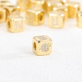 Macro shot of 18K gold plated dice bead featuring zircon inlays and a Saturn motif - Zirconia Planet Pendant