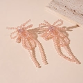 Detailed shot of pink crystal beaded bow earrings with soft tassels on stone surface - Champagne Pink