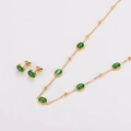 Détail macro d'un ensemble collier et boucles d'oreilles dorés avec émeraudes ovales - Doré