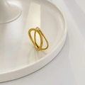 Macro view of gold minimalist interlocking wave ring on a white display plate - Crisscross Double Layer
