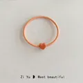 Elastic candy-colored orange hair tie with a matte heart-shaped charm and braided rope - Orange