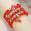 Detailed view of layered red beaded bracelets with LOVE and KISS charms on a display stand - Red White KISS/LOVE Heart Set