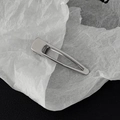 Dettaglio macro di un fermaglio per capelli in metallo argentato lucido su sfondo testurizzato - Stile Ovale Goccia Argento