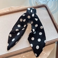 Detailopname van haarklem met zwarte polkadot stoffen strik op een houten blad - Grote stippen / Zwart
