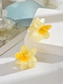 Close-up of translucent yellow flower hair claws on a white stone pedestal - Yellow (Single Piece)