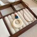 Close-up of a resin pendant necklace with beads on a wooden jewelry box display - 66# Necklace-White-Round