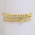 Set di tre braccialetti a sfere dorate con ciondolo lettera B su espositore - Lettera B