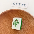 Quirky Mahjong tile hair clip featuring the classic green bird design on a wooden tray - Yao Ji (1 of Bamboos)