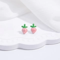 Detail view of pink carrot stud earrings with green leaves on white lace tray - Pink Carrot