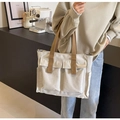 Nahaufnahme einer beigen Canvas-Handtasche mit braunen Trägern und Pattentaschen - Gebrochenes Weiß