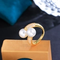 Dettaglio anello dorato con doppia perla e pavé di zirconi su supporto di lusso - Oro