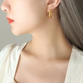 Golden C-shaped earrings with layered shell design worn by model for elegant style - Gold