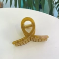 Détail macro d'une pince à cheveux en acrylique ambre avec ressort en métal doré - Moyen / Jaune d'automne